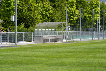 Fototapeta na wymiar Fresh mowed empty football field with covered bench at springtime. Photo taken May 27th, 2021, Zurich, Switzerland.