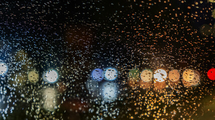 rain drops on the window surface with traffic bokeh light in background