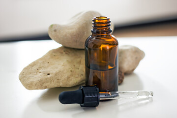 Natural wellness cosmetics background. Glass cosmetic bottle with a dark glass pipette on a...