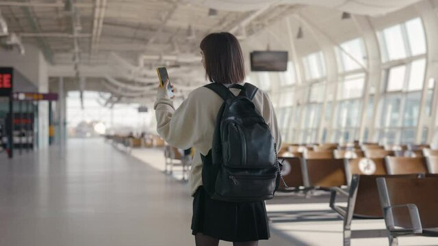 Female tourist using cell phone while walking at airport