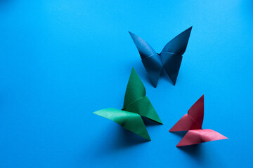 multicolored origami paper butterflies on blue paper background