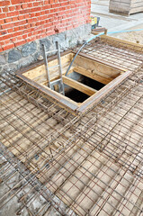 Cellar entrance surrounded by ribbed steel bar reinforcement construction frame ready for concrete casting.