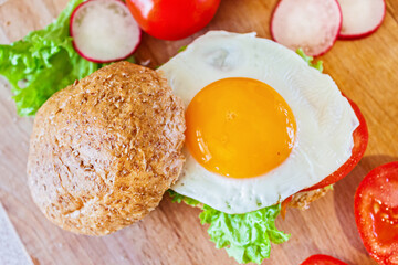 A healthy breakfast. Bun with lettuce, tomatoes and egg.