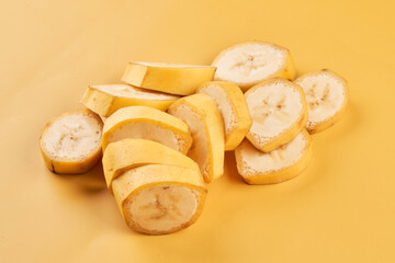 Sliced bananas on yellow background close up, healthy dessert ingredient