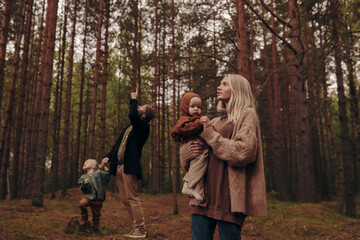 Fototapeta premium Happy family with children on a walk in the park among the trees.