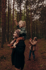 Happy family with children on a walk in the park among the trees.