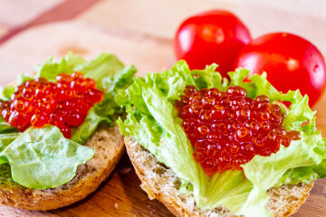 On the bun is a lettuce leaf and red caviar close-up.