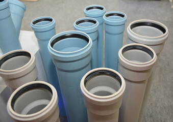 The display of plastic white and blue sewer pipes, underground drain pipes in a shop. Choosing PVC sewer drain pipes.