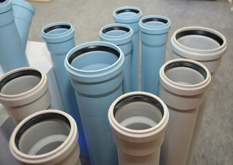 Naklejka premium The display of plastic white and blue sewer pipes, underground drain pipes in a shop. Choosing PVC sewer drain pipes.