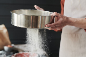 Close-up of young woman baking with the flour in the kitchen