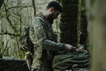 Portrait of airsoft player in professional equipment with machine gun in the forest. Soldier with weapons at war