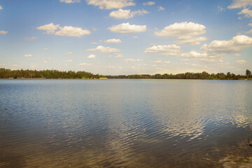 The blue lake reflects the sky and clouds. It's a sunny summer day.