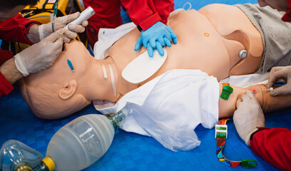 A paramedic with blue rubber gloves shows how to resuscitate a doll's heart. First aid exercise