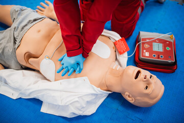 A man with blue rubber gloves practices giving artificial respiration to a doll. Exercise first aid