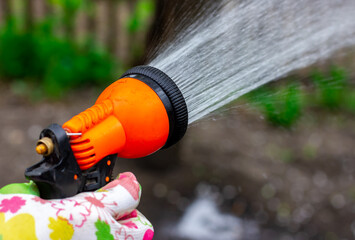 Water spray for the garden. Watering the garden. Watering your backyard garden. Watering gun in hand.