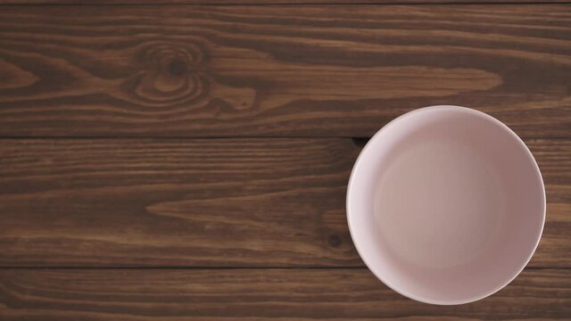 Female hands put three empty bowls on a wooden textured table. Three bowls next to each other on the kitchen table. Three color options: pastel pink, pastel green and pastel blue. Top view. Trendy pas