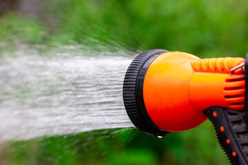 Orange water spray. Watering the green garden. Water gun for watering.