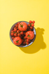 Ripe juicy tomatoes on a bright yellow background, trendy shadows. Summer vegetables, pop art style