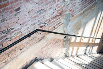 Staircase with industrial brick wall and railing with night light and shadow. Looking down