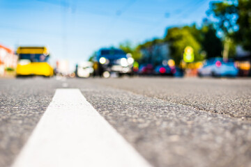 Sunny day in a city, the bus is at the bus stop next to passing cars, the view from the level of asphalt