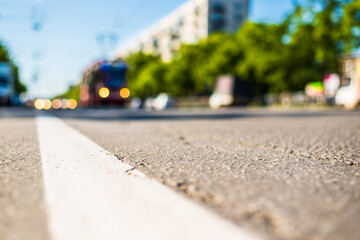 Sunny day in a city, tram rides on rails next to the stream of cars, the view from the level of asphalt