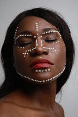 Portrait of attractive young black woman with pearls on her face. Vertical.