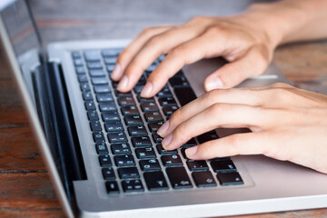 Hands typing on laptop computer keyboard, writing email or contacting people