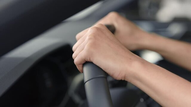 Close up of steering wheel with female hands on it