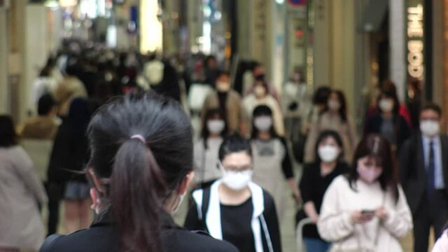 OSAKA, JAPAN - APRIL 2021 : Crowd of people wearing surgical masks to protect from Coronavirus (COVID-19) at in busy rush hour. View around Namba, Shinsaibashi downtown shopping street.