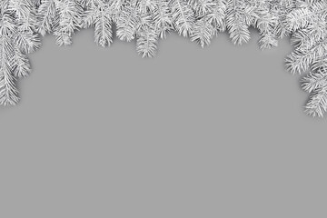 Festive composition with border of fluffy light gray fir branches on gray background. Trendy monochrome xmas template. Top view, flat lay style, copy space for text.