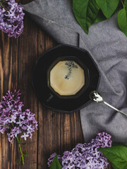 Coffee cup on a wooden background with lilac branches