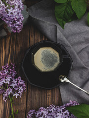 Obraz na płótnie Canvas Coffee cup on a wooden background with lilac branches