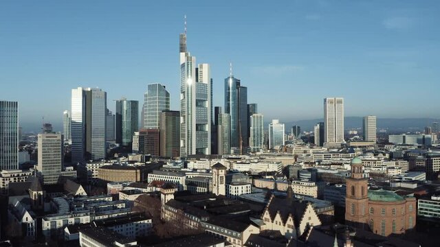Panorama Drohnenaufnahme der Skyline Frankfurt mit Altstadt im Vordergrund und dem Bankenviertel im Hintergrund bei sonnigem Wetter. Kamera fährt senkrecht nach oben
