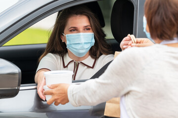 Woman in a car being delivered takeaway and a paper bag: Selective focus. Safety concept.