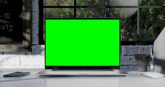 Modern laptop with blank green screen. Static footage with trees swaying or moving in the wind. Home interior or loft office background, 4k 30fps UHD, loop video
