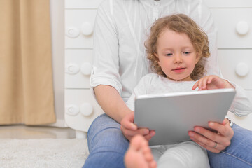 A little girl with her mother looks at the tablet computer. Children and gadgets.