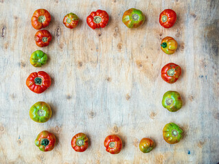 Tomatoes of different sizes and textures, organic and ecological, arranged in a square shape on a wooden board.