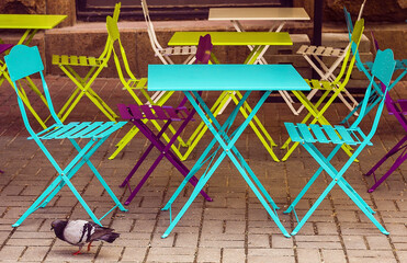 Multi-colored little tables and stools on the street. Color iron tables .  Cafe on the street