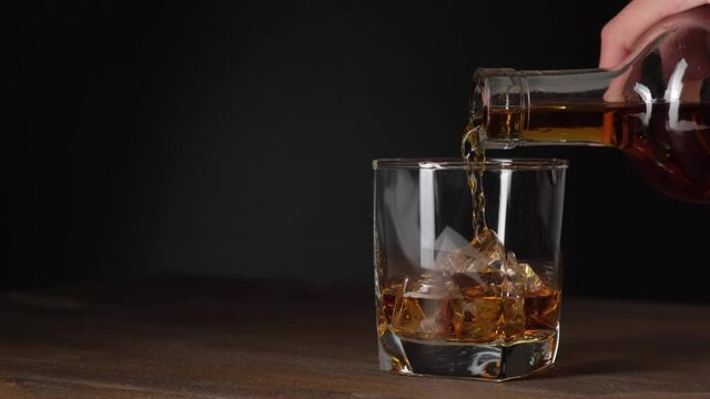 Pouring whiskey in glasses with ice cubes. Cinemagraph.