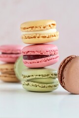 Colourful macarons stack on pale pink background