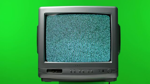 Old TV set in the studio on a green screen of chroma key. White noise effect on the screen. Analog Static Noise texture. Monochrome, black and white offset flicker. Screen damage. Close up.