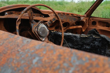 A rusty car wreck standing in the grass