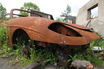 A rusty car wreck standing in the grass