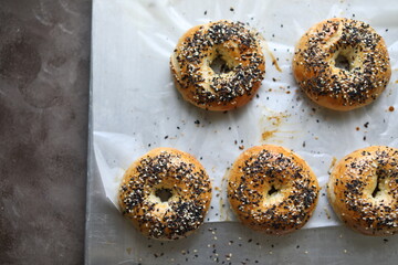 Ruddy bagels with sesame seeds and poppy seeds on a baking sheet. Traditional pastries.