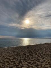 Obraz premium Sandy beach with peering sun through the evening clouds
