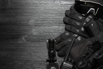 Airsoft guns, gloves, radio station, knife, glasses and soldier badge on the black flat lay...