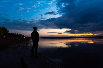Fototapeta premium Russia. May 16, 2021. The figure of a man on the pier on the Sukhodolsky lake before dawn.