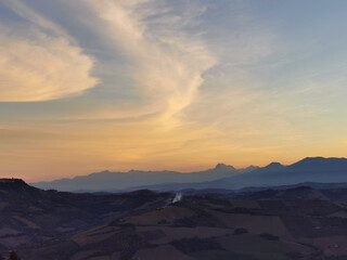 Montagne e valli in un luminoso tramonto di nuvole color arancio