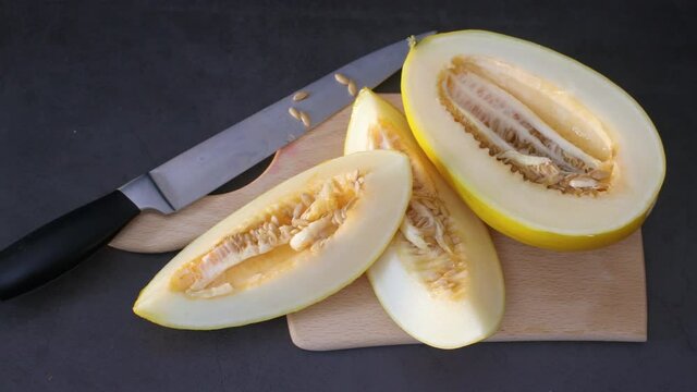 Sliced honey melon on cutting board on the table with knife