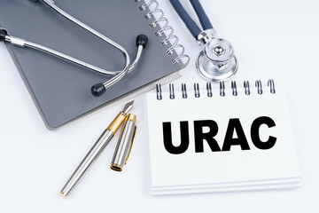 On the table are a stethoscope, a pen and a notebook with the inscription - Urac